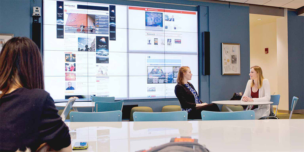 Students sitting at tables in the Global lounge at HLS.