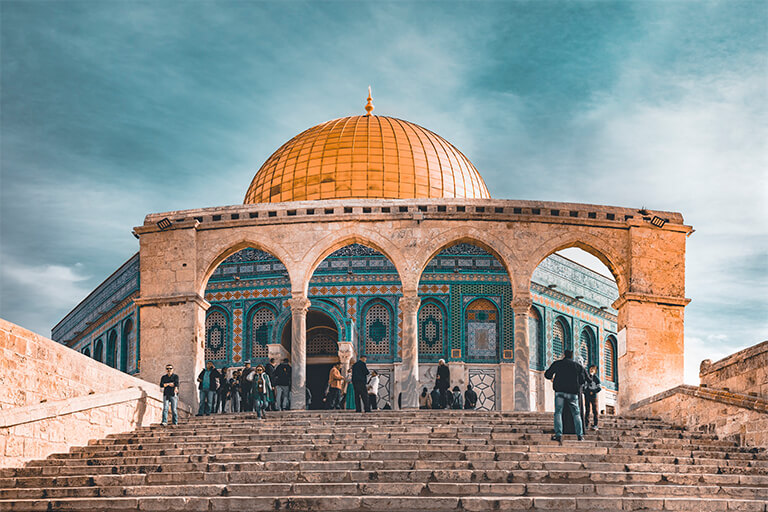 A mosque with people walking up some stairs.