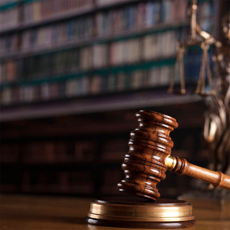 A gavel with books on a shelf in the background.